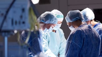Surgeons in operating room with air quality monitors on.