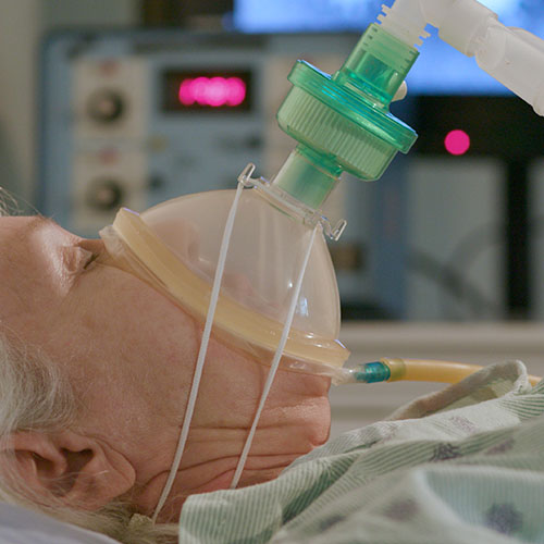COVID-19 patient using a medical ventilator for breathing support.